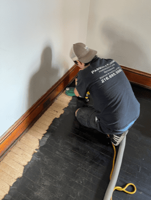 person working on hardwood floor with black covering