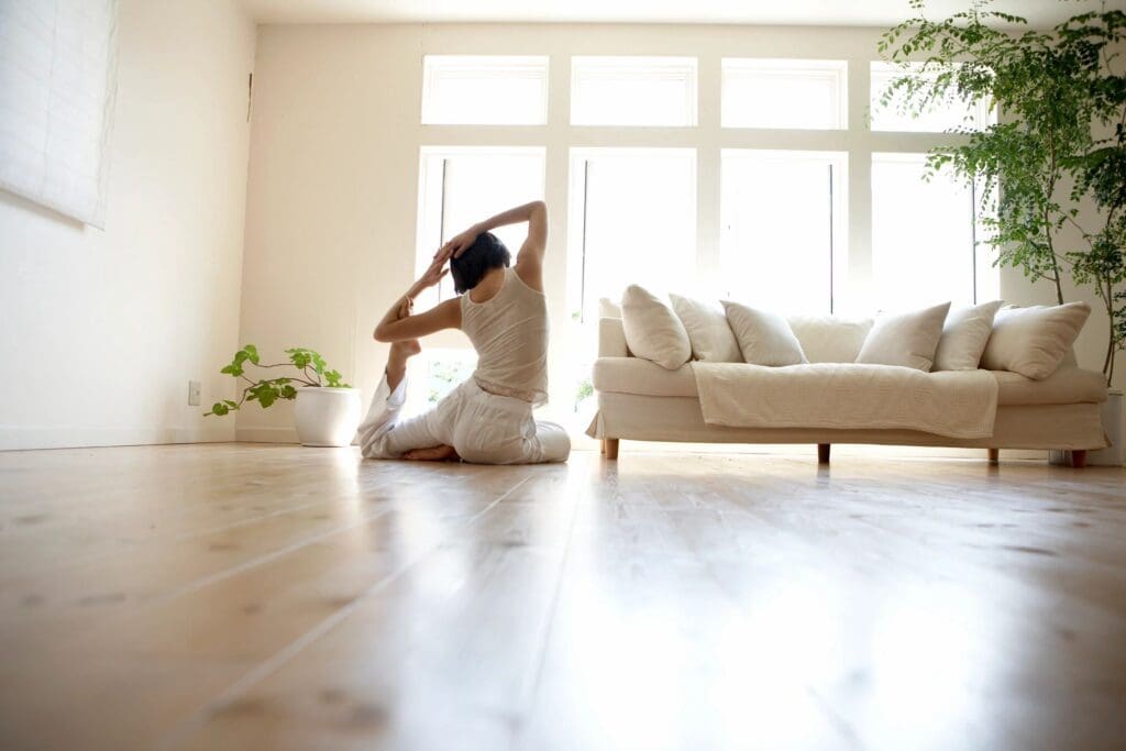 woman stretching in front of windows and a white couch
