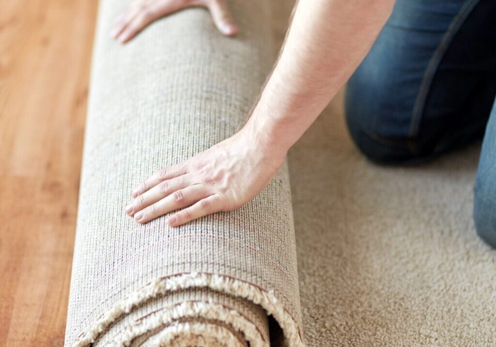 A person rolling out a cream colored carpet