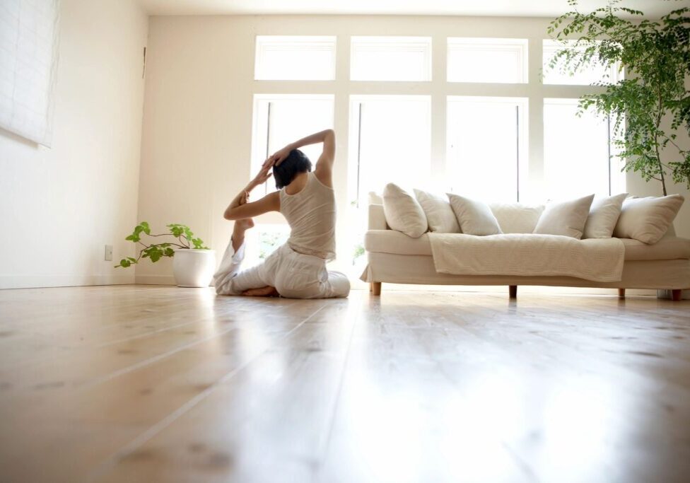 woman stretching in front of windows and a white couch